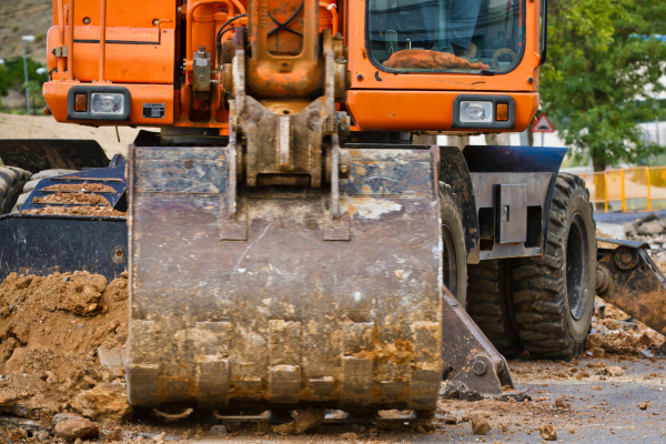 An orange excavator working in a construction zone